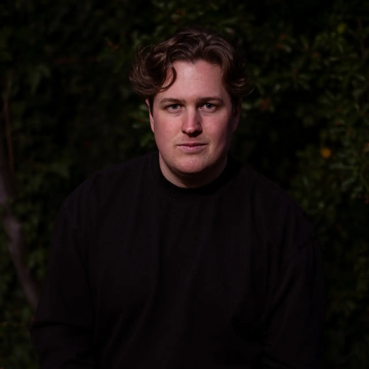 Jake Kenning, lit warmly against dark foliage