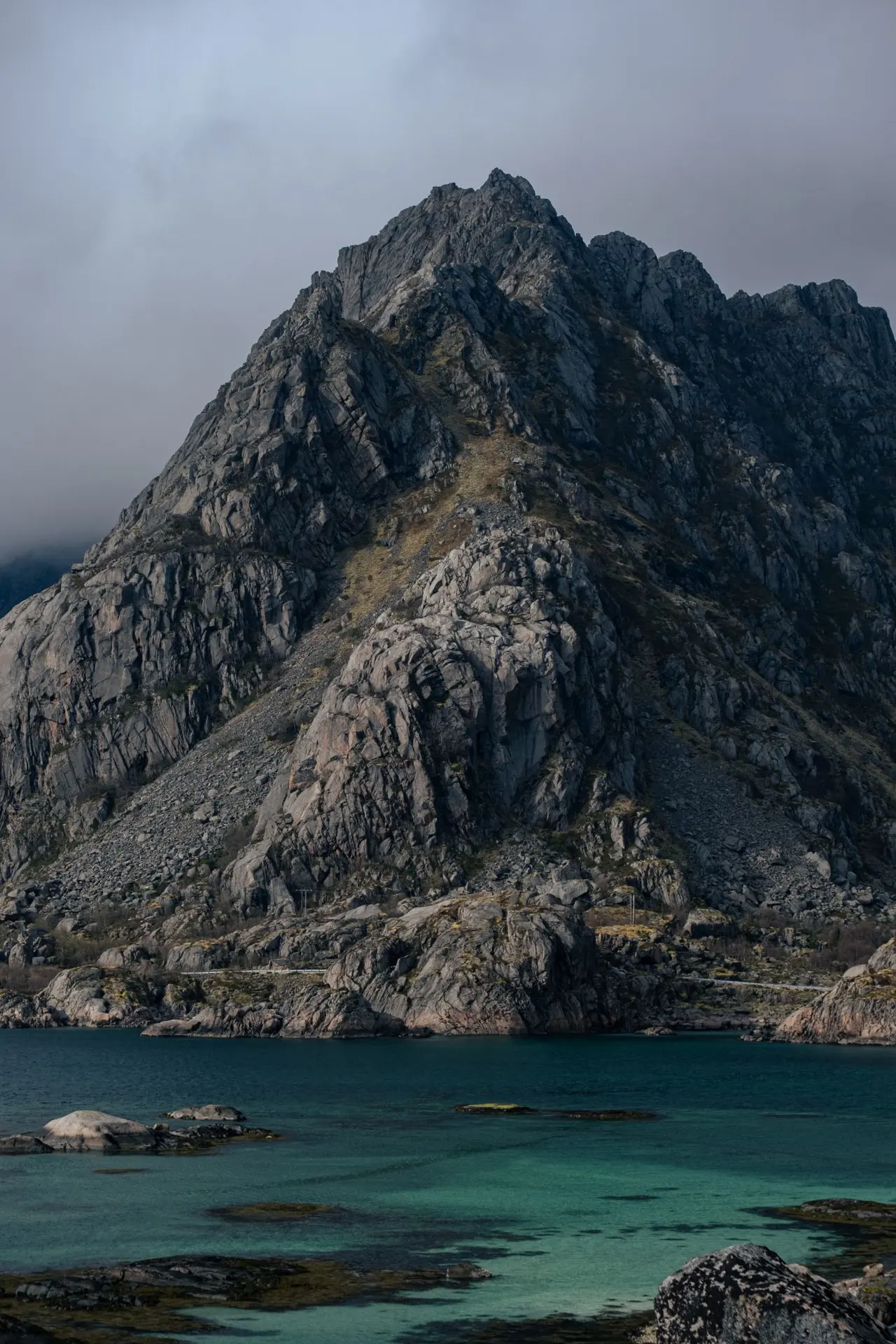 A sharp granite peak above a turquoise fjord